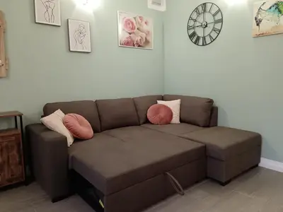 a brown couch in a living room with a clock on the wall at Casa MARGHERITA in Grumes