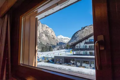 a view of a snowy mountain from a window at Week End Senoner in Selva di Val Gardena