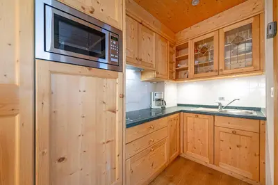 a kitchen with wooden cabinets and a microwave at Week End Senoner in Selva di Val Gardena