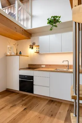 a kitchen with white cabinets and a black dishwasher at KARINA Mulino in Montagna