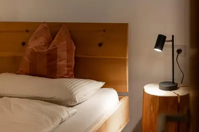 a bedroom with a bed with a wooden headboard and a lamp at KARINA Mulino in Montagna