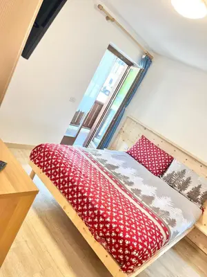 a bedroom with a bed with red and white pillows at CASA MARILU' in Castello di Fiemme