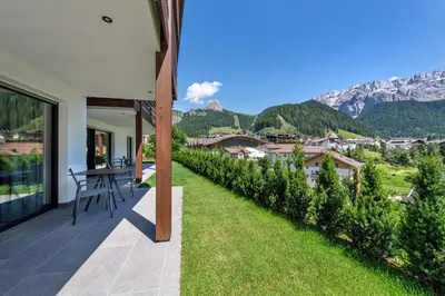 a balcony of a house with a table and green grass at Apartments Chalet Silva in Selva di Val Gardena
