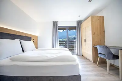 a bedroom with a bed and a desk and a window at Apartments Chalet Silva in Selva di Val Gardena
