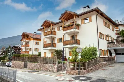 a large white building with balconies on a street at Cristina Hospitality in Ortisei