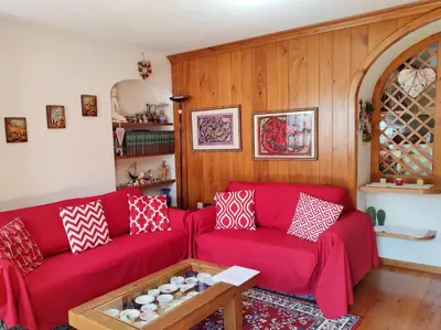 a living room with a red couch and a table at Casa Amabile in San Vito di Cadore