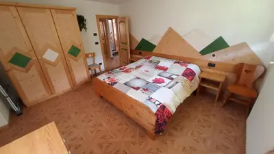 a bedroom with a bed and a wooden wall at Appartamento Zanoner Lorenzo in Moena