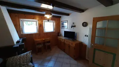 a living room with a television and a desk with a computer at Appartamento Zanoner Lorenzo in Moena