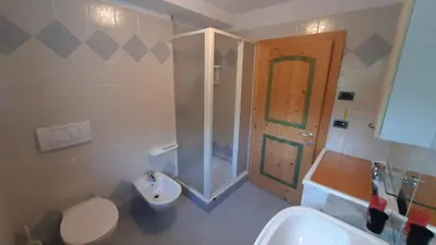 a bathroom with a toilet and a sink and a door at Appartamento Zanoner Lorenzo in Moena
