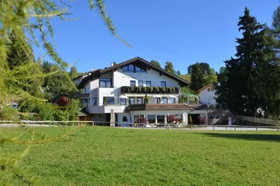 a large white house on a hill with a green field at Hotel Gasthof Wieser in Petersberg
