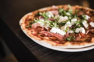 a pizza sitting on a plate on a table at Hotel Gasthof Wieser in Petersberg