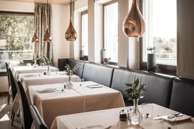 a row of tables in a restaurant with white table cloth at Hotel Gasthof Wieser in Petersberg