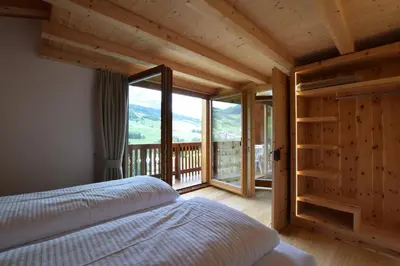 a bedroom with a bed and a large window at Ciasa Lisüra in Badia