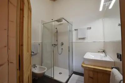 a bathroom with a glass shower and a sink at Ciasa Lisüra in Badia