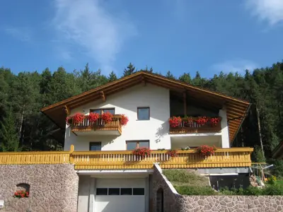 a white building with red flowers on its balcony at Polzhof in Castelrotto