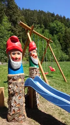 two wooden puppets standing next to a swing at Polzhof in Castelrotto