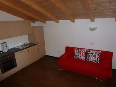 a living room with a red couch and a kitchen at Polzhof in Castelrotto