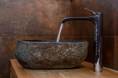 a stone sink with a water fountain in a bathroom at Ciasa Marizana in Soraga