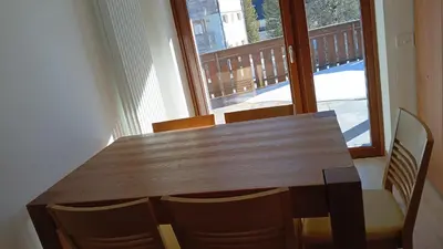 a wooden table and chairs in a room with a window at Appartamento con terrazza vista Pale di San Martino in San Martino di Castrozza