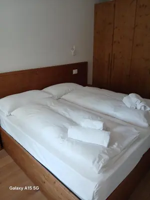 a bed with white sheets and towels on it at Appartamento con terrazza vista Pale di San Martino in San Martino di Castrozza
