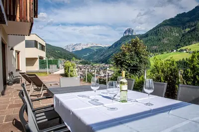 a table with wine glasses on a balcony with mountains at Villa Vastle in Ortisei
