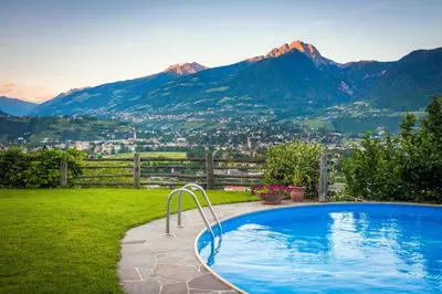 a swimming pool in a yard with mountains in the background at Weingut Pardellerhof in Marlengo