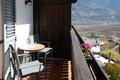 a balcony with a table and chairs and a door at Weingut Pardellerhof in Marlengo