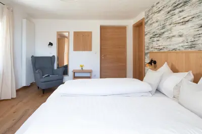 a hotel room with two beds and a chair at Weingut Pardellerhof in Marlengo