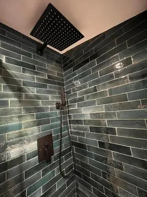 a shower in a bathroom with a brick wall at Casa Karin in Canazei