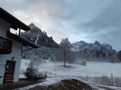a snow covered field with mountains in the background at Locanda Val Canali in Siror