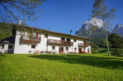a large white building with balconies on a green field at Locanda Val Canali in Siror