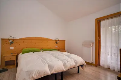a bedroom with a bed with a wooden headboard and a window at Locanda Val Canali in Siror
