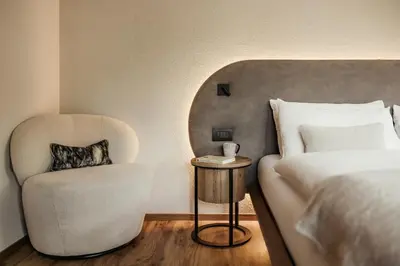 a bedroom with a bed and a chair next to a bed at Apartments Villa Sofia in Santa Cristina in Val Gardena