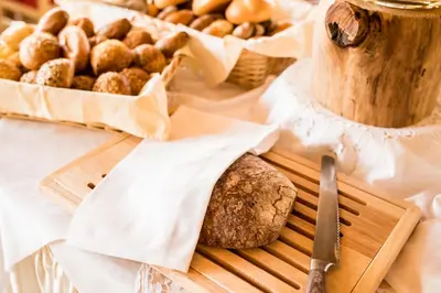 a table with a cutting board with bread and a knife at Hotel Schallerhof in Tesimo