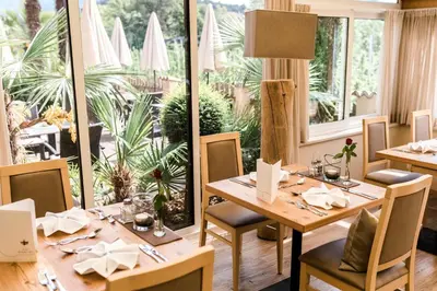 a dining room with tables and chairs and a large window at Hotel Schallerhof in Tesimo