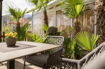 a table and chairs on a patio with palm trees at Hotel Schallerhof in Tesimo