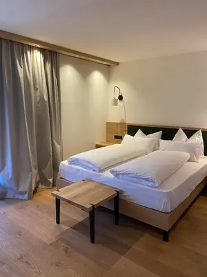 a bedroom with two beds and a table at Hotel Mühlenerhof in Campo Tures