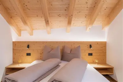 a bedroom with wooden ceilings and a bed with pillows at App Mittermairhof in Riscone