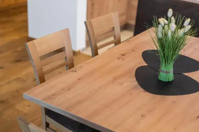 a wooden table with a vase of flowers on it at App Mittermairhof in Riscone