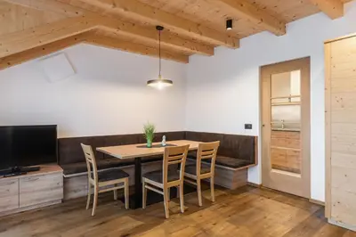a dining room with a table and chairs and a television at App Mittermairhof in Riscone