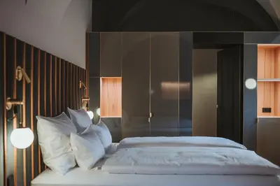 a bedroom with a bed with white sheets and pillows at Arthotel Lasserhaus in Bressanone