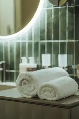 two rolled towels sitting on a table in a bathroom at Arthotel Lasserhaus in Bressanone