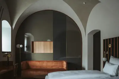 a bedroom with a bed and a couch and a mirror at Arthotel Lasserhaus in Bressanone