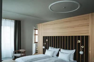 a bedroom with a large bed with a wooden headboard at Arthotel Lasserhaus in Bressanone