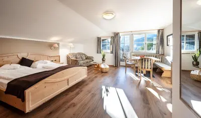 a bedroom with a bed and a living room at Alpwellhotel Burggräfler in Tesimo