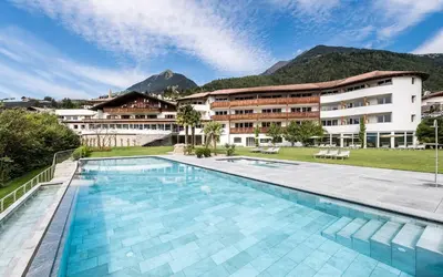 a hotel with a swimming pool in front of a building at Hotel Hofbrunn in Rifiano