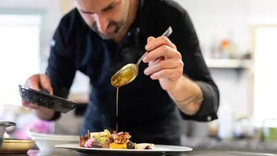 a man pouring sauce onto a plate of food at Ladurner in Lagundo