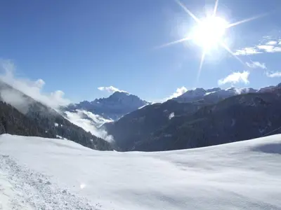 a snow covered mountain with the sun in the sky at Dolomites Base Camp Hotel Olympia in Arabba