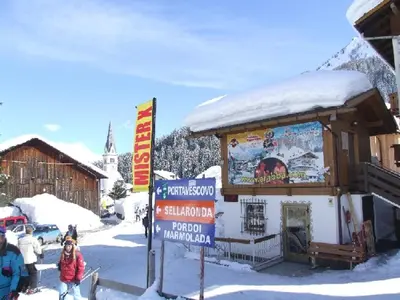 a small building with a sign in the snow at Dolomites Base Camp Hotel Olympia in Arabba