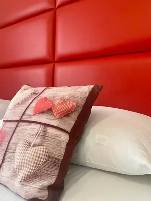 a pillow with hearts on it sitting on a bed at Dolomites Base Camp Hotel Olympia in Arabba